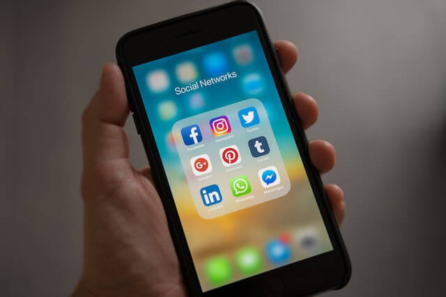 Mano sosteniendo celular con redes sociales en la pantalla
